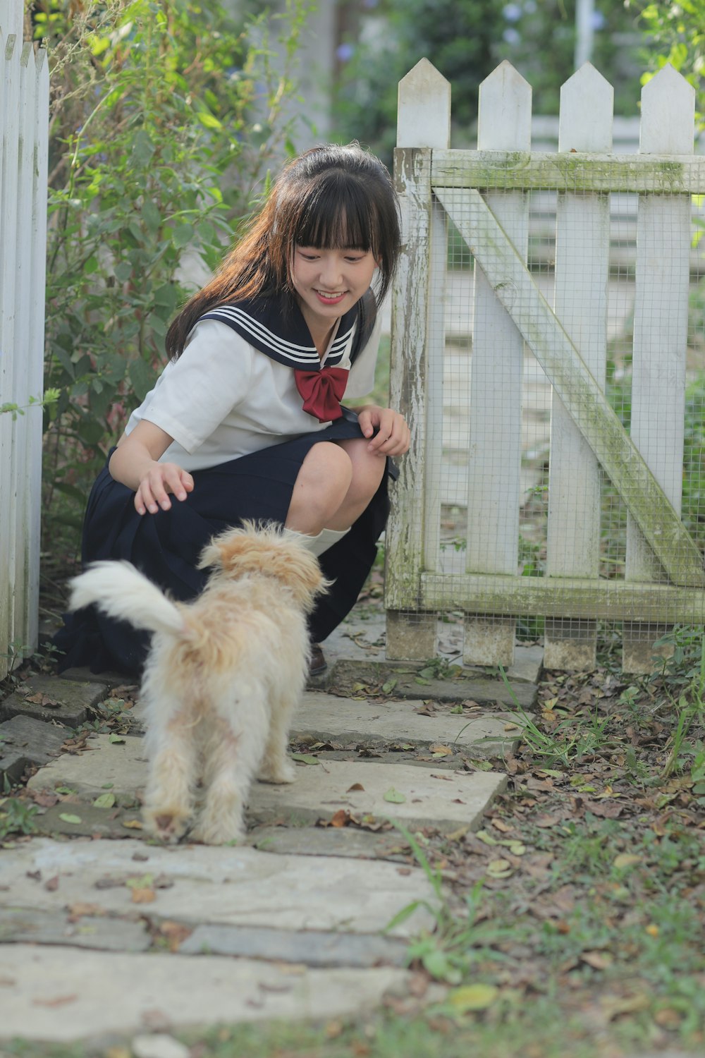 a little girl kneeling down next to a dog