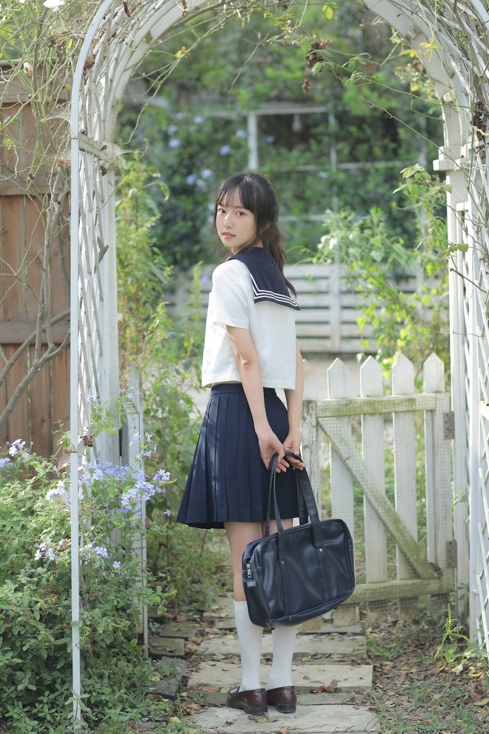 a woman in a white shirt and black skirt carrying a black bag