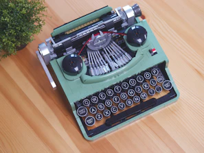 a green typewriter sitting on top of a wooden table