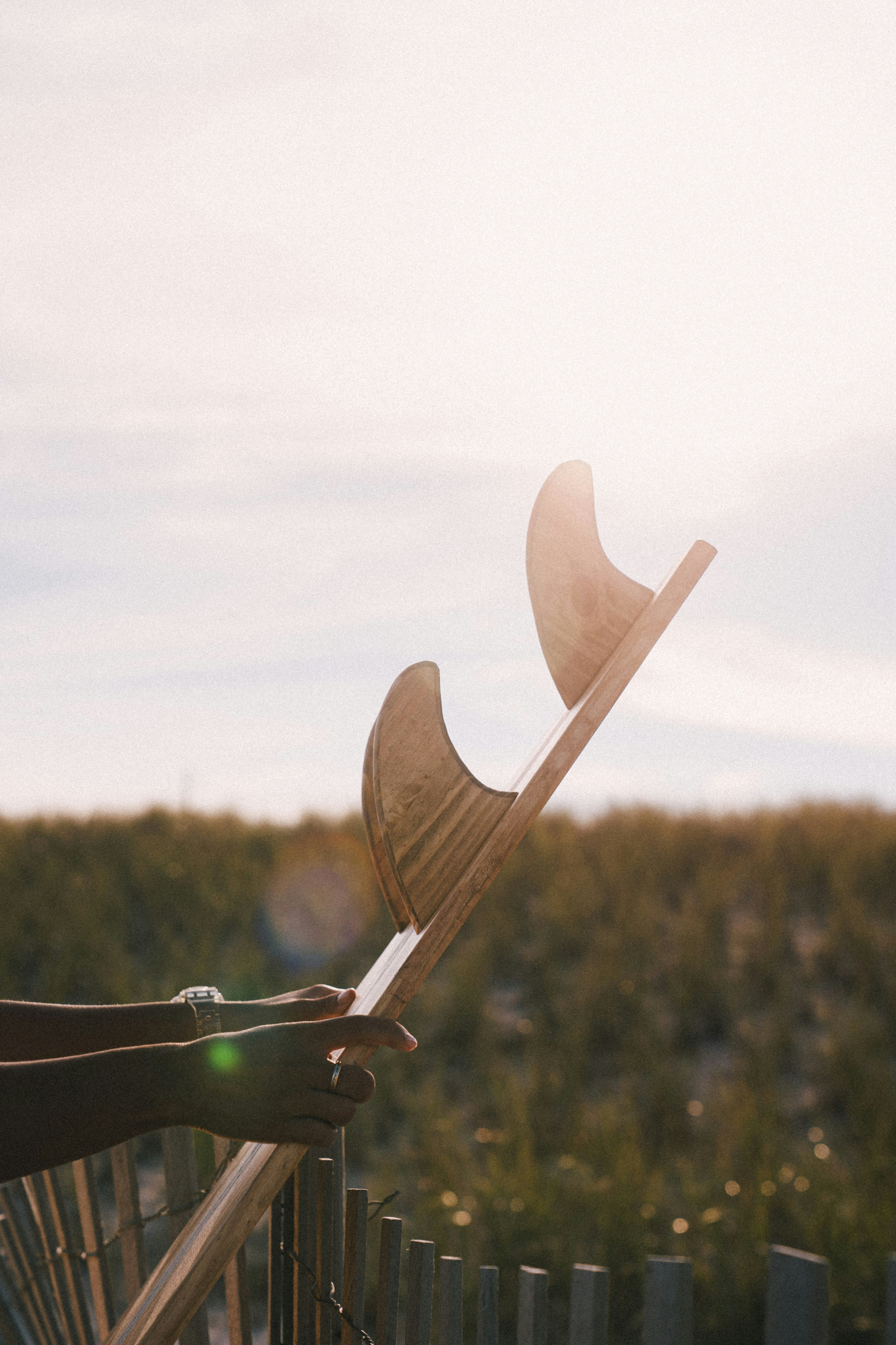a person leaning on a fence holding a pair of skis