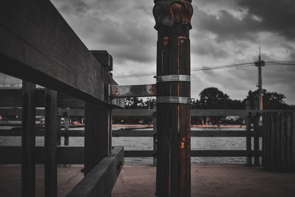 a black and white photo of a fence and a body of water