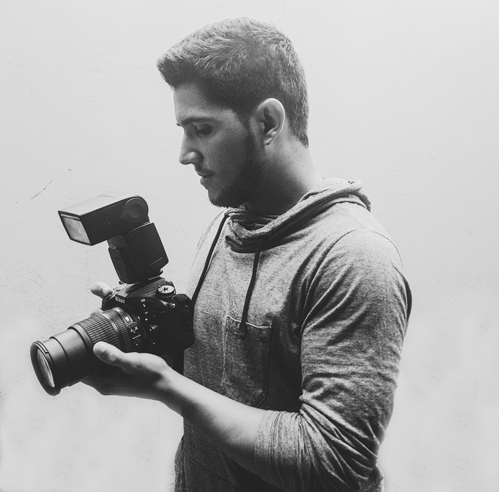 a black and white photo of a man holding a camera