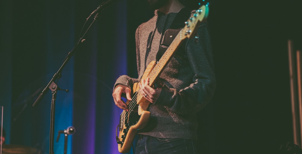 a man standing in front of a microphone while playing a guitar