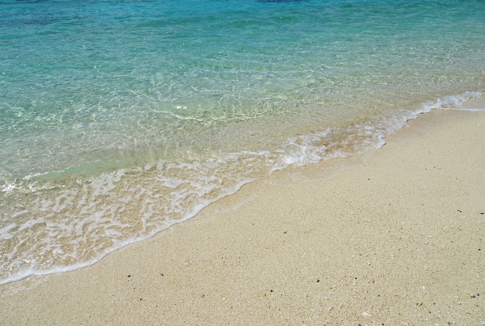 a sandy beach with a wave coming in to shore