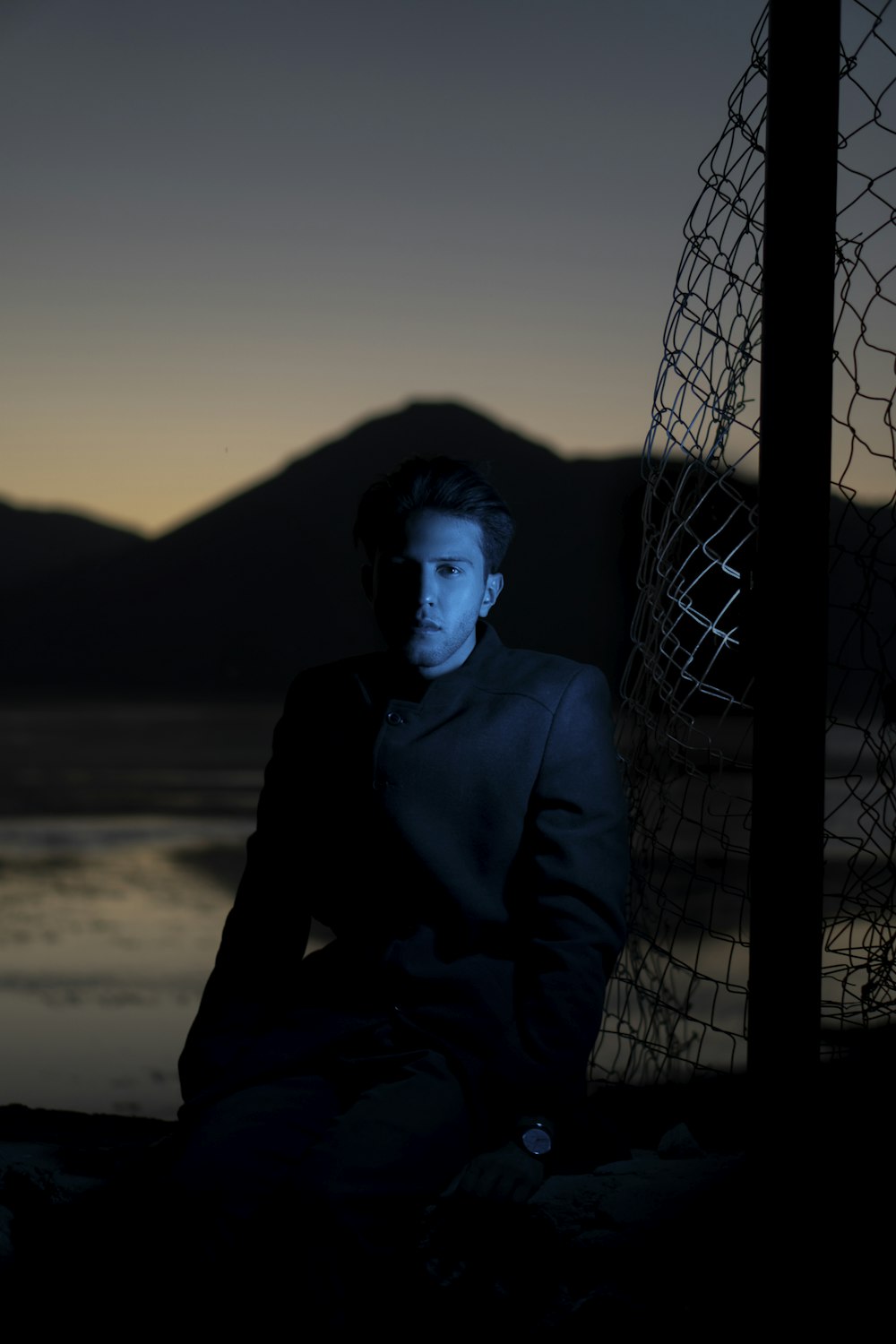 a man sitting on the ground next to a net