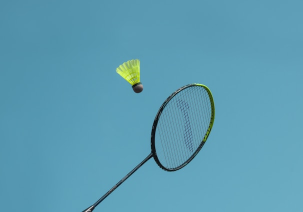 a badminton racket and a yellow frisbee flying in the air