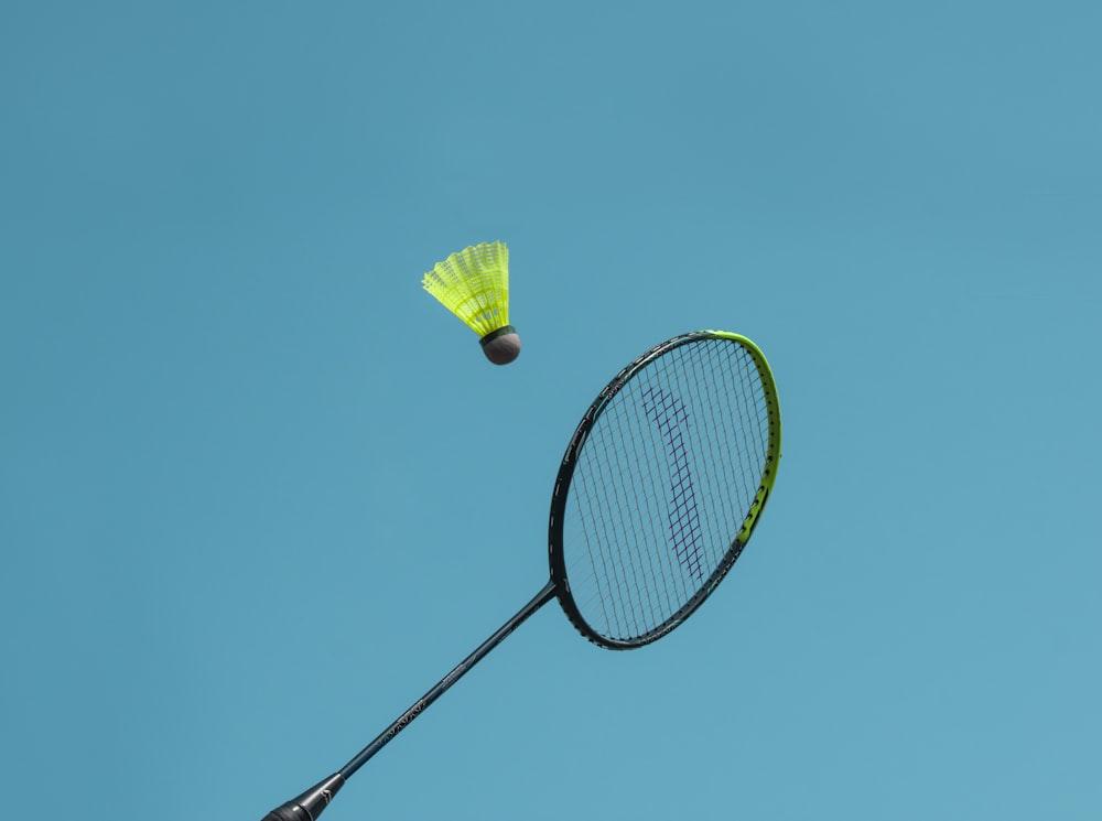 a badminton racket and a yellow frisbee flying in the air