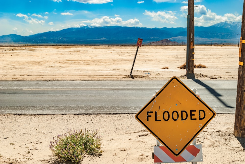 a yellow flood sign sitting on the side of a road