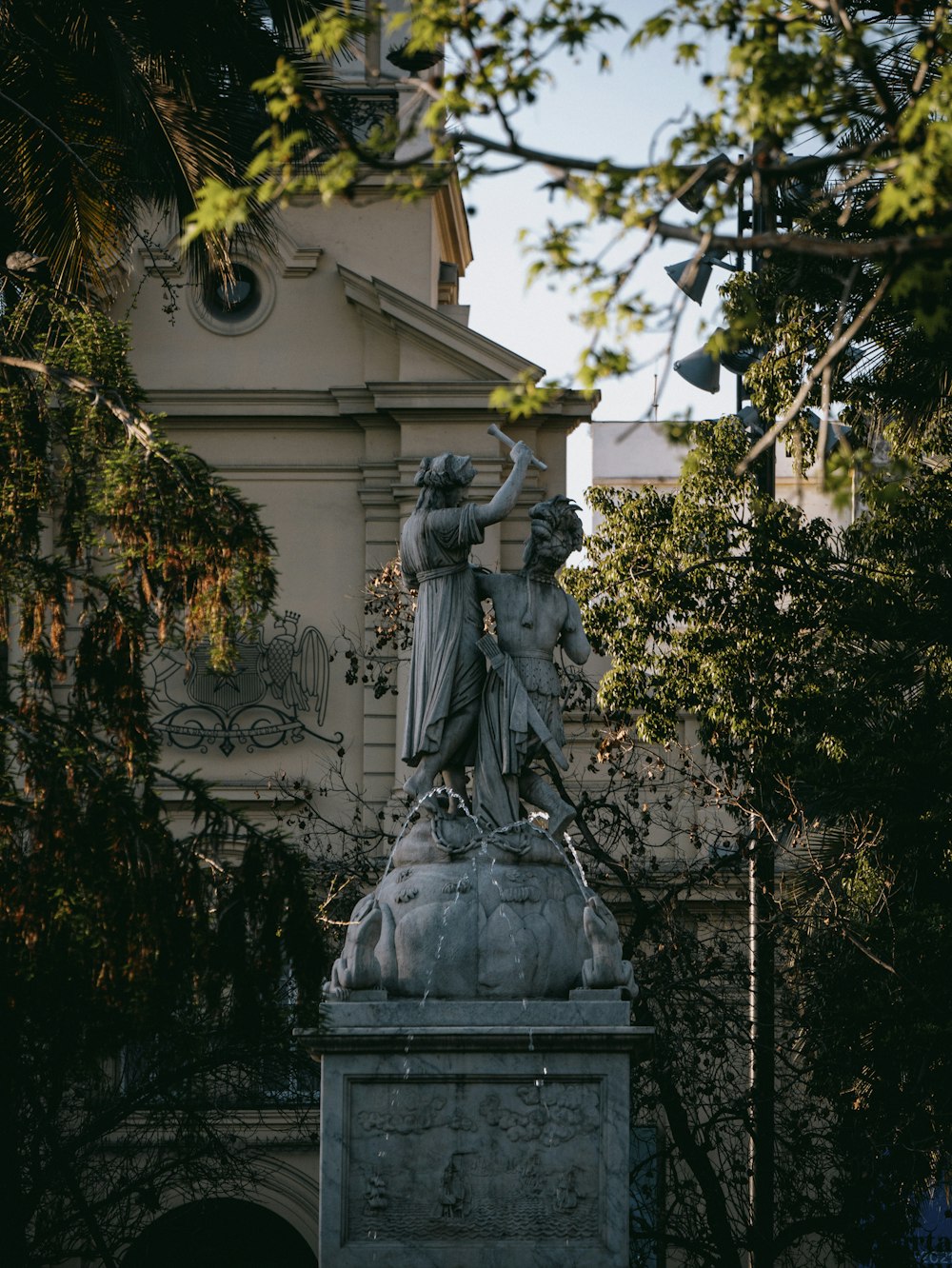 Una estatua frente a un edificio con una torre del reloj