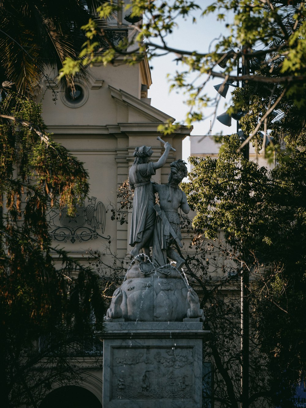 uma estátua em frente a um edifício com uma torre do relógio