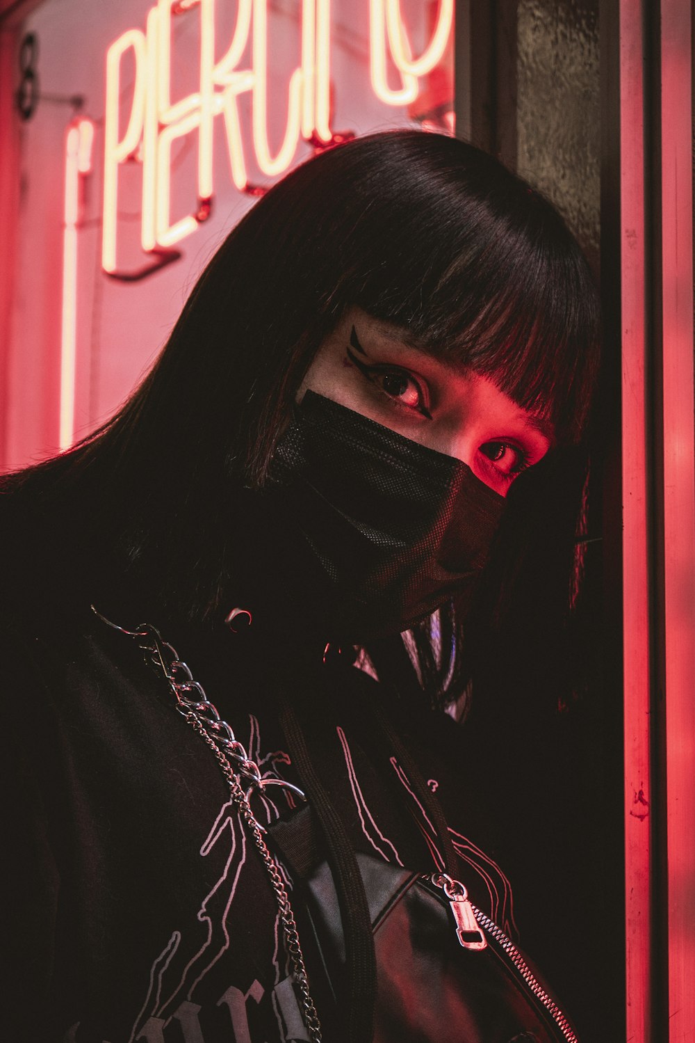 a woman with black hair wearing a black mask