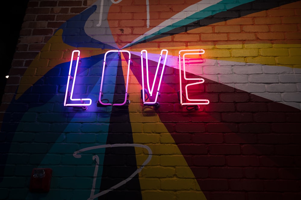 a neon sign that says love on a brick wall