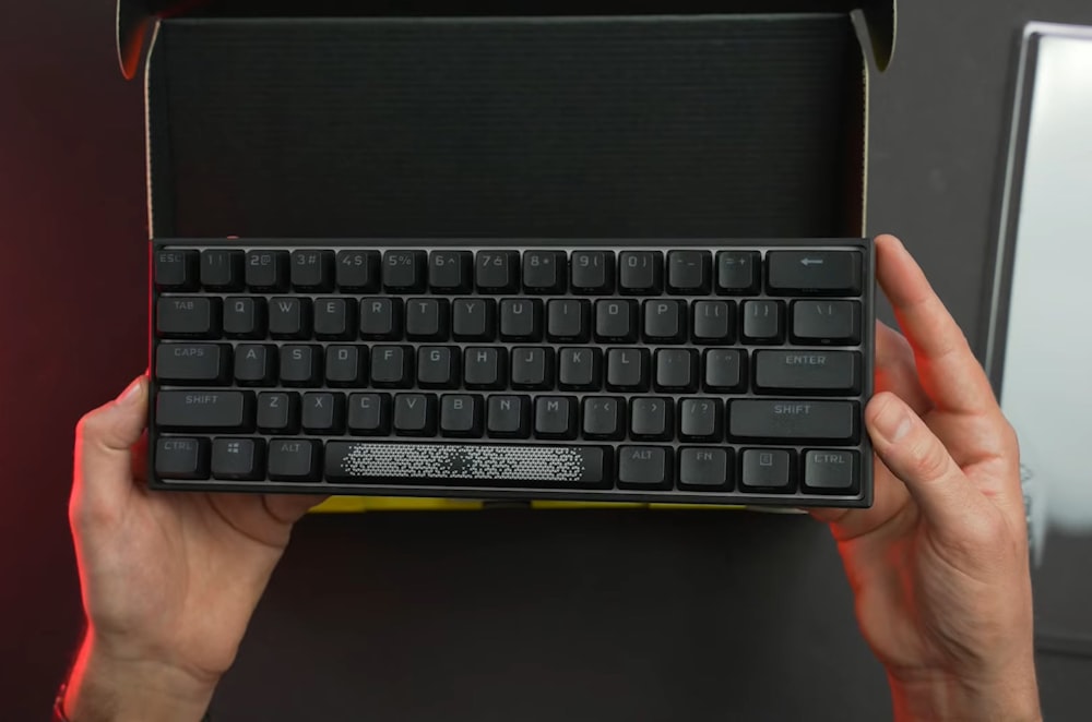 a person holding a black keyboard in front of a box