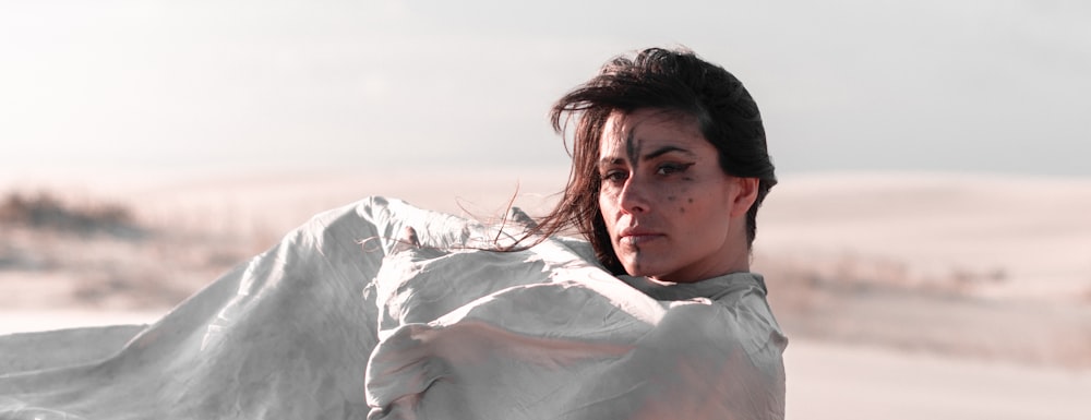 a woman in a white dress standing in the sand