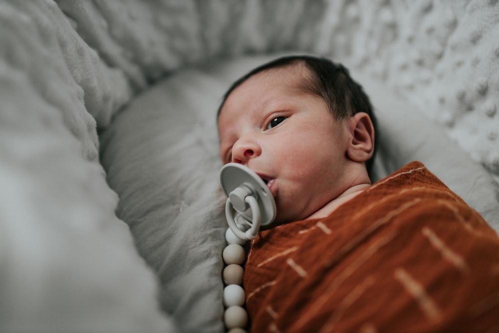 a baby laying in a crib with a pacifier in it's mouth