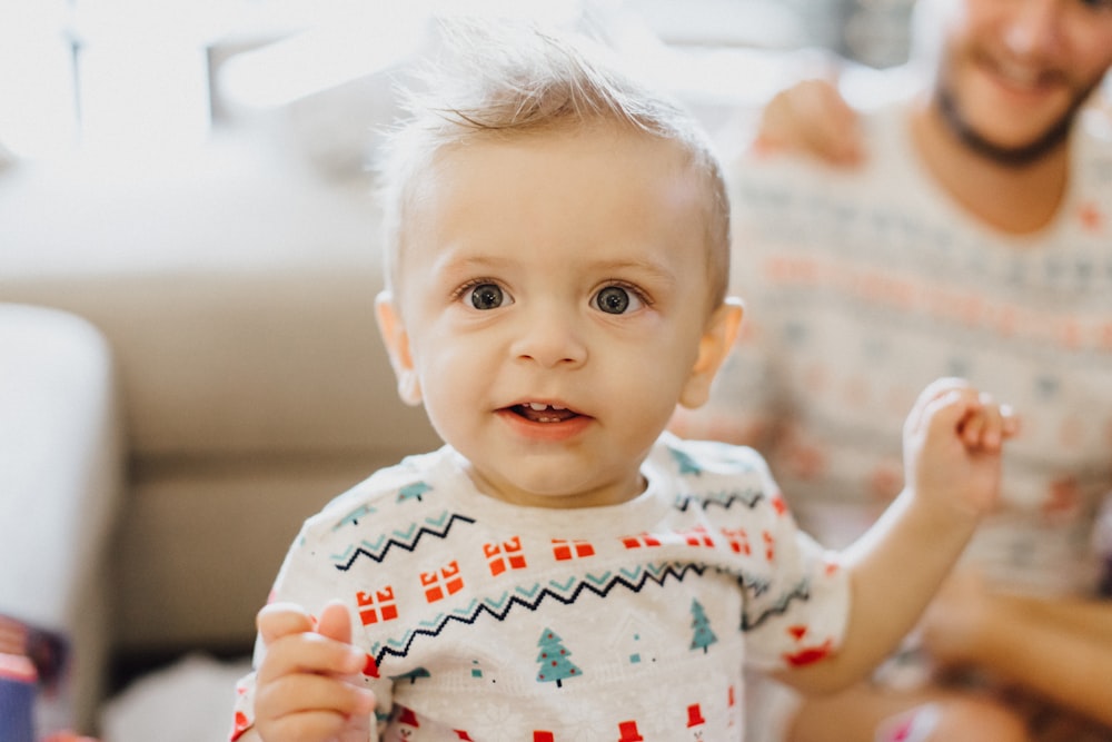 a baby is sitting on a couch with a man in the background