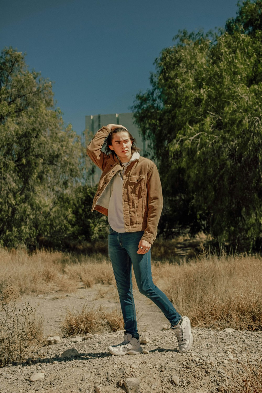 a man in a brown jacket is walking in a field