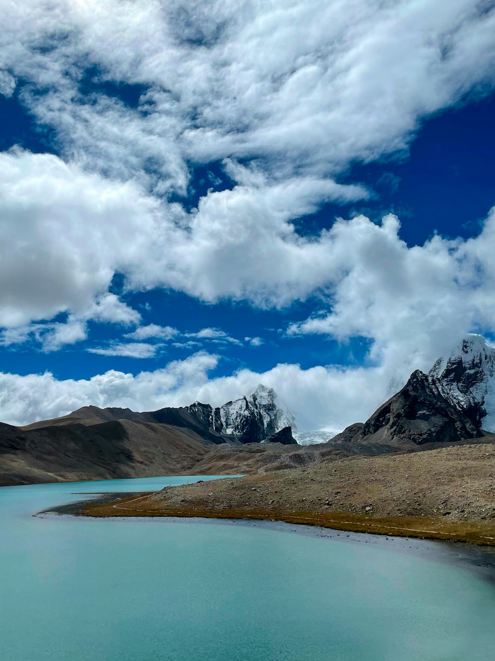 a body of water surrounded by mountains under a cloudy sky