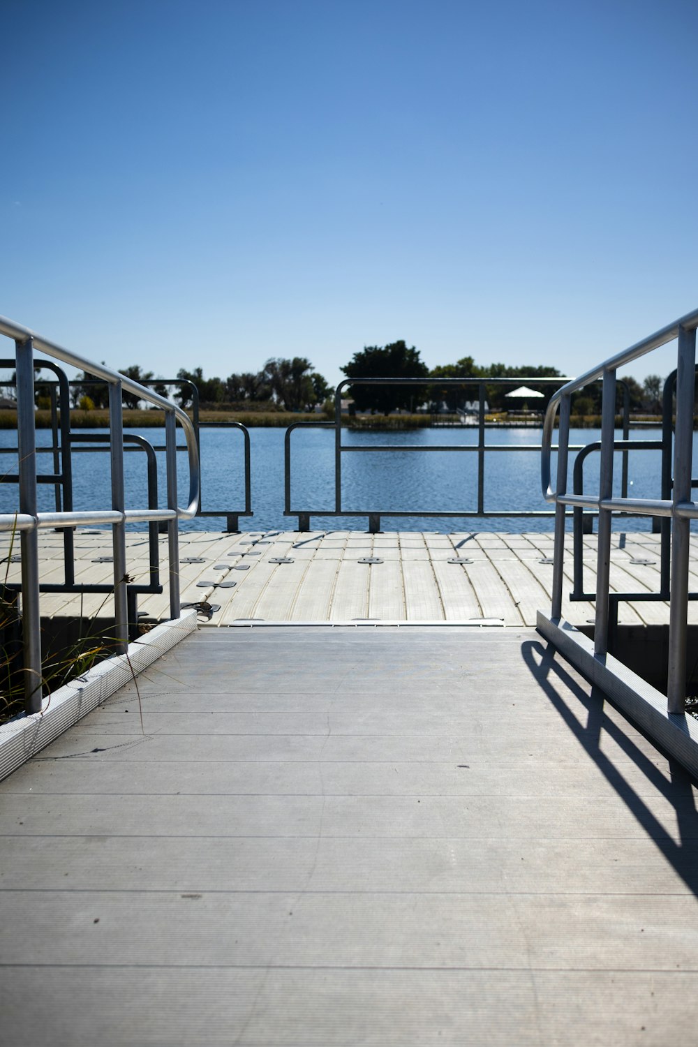 a wooden dock with metal railings next to a body of water