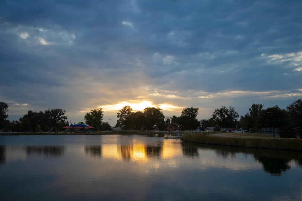 the sun is setting over a lake in a park