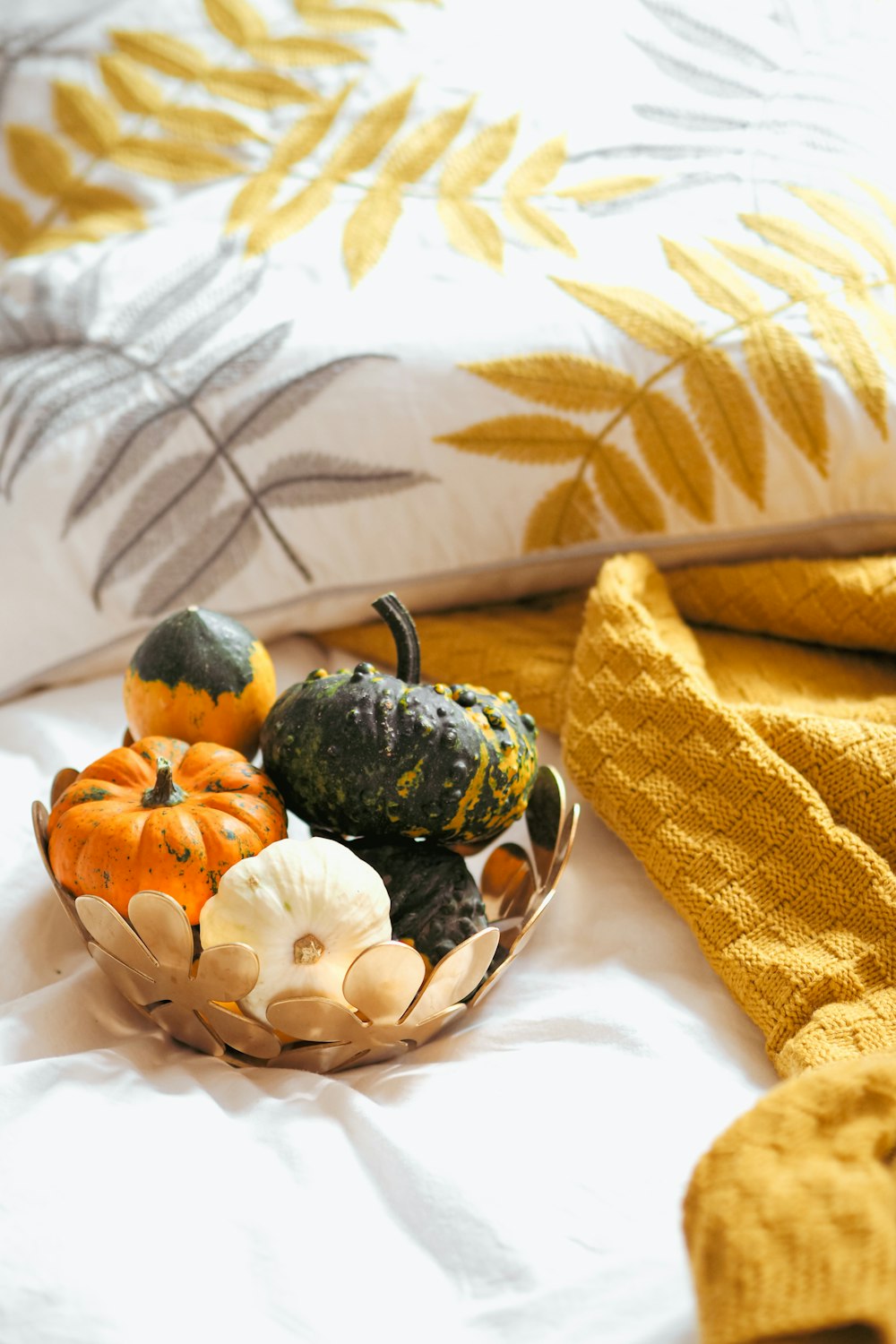 a basket of gourds and squash on a bed