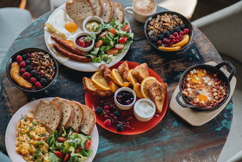 a table topped with plates of food and bowls of fruit