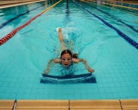 a young girl swimming in a pool with her head above the water