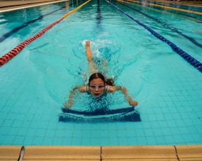 a young girl swimming in a pool with her head above the water