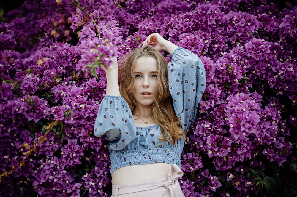 a woman standing in front of purple flowers