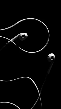 An artistic capture of a minimalist black headset with bold white branding, set against a seamless black backdrop.