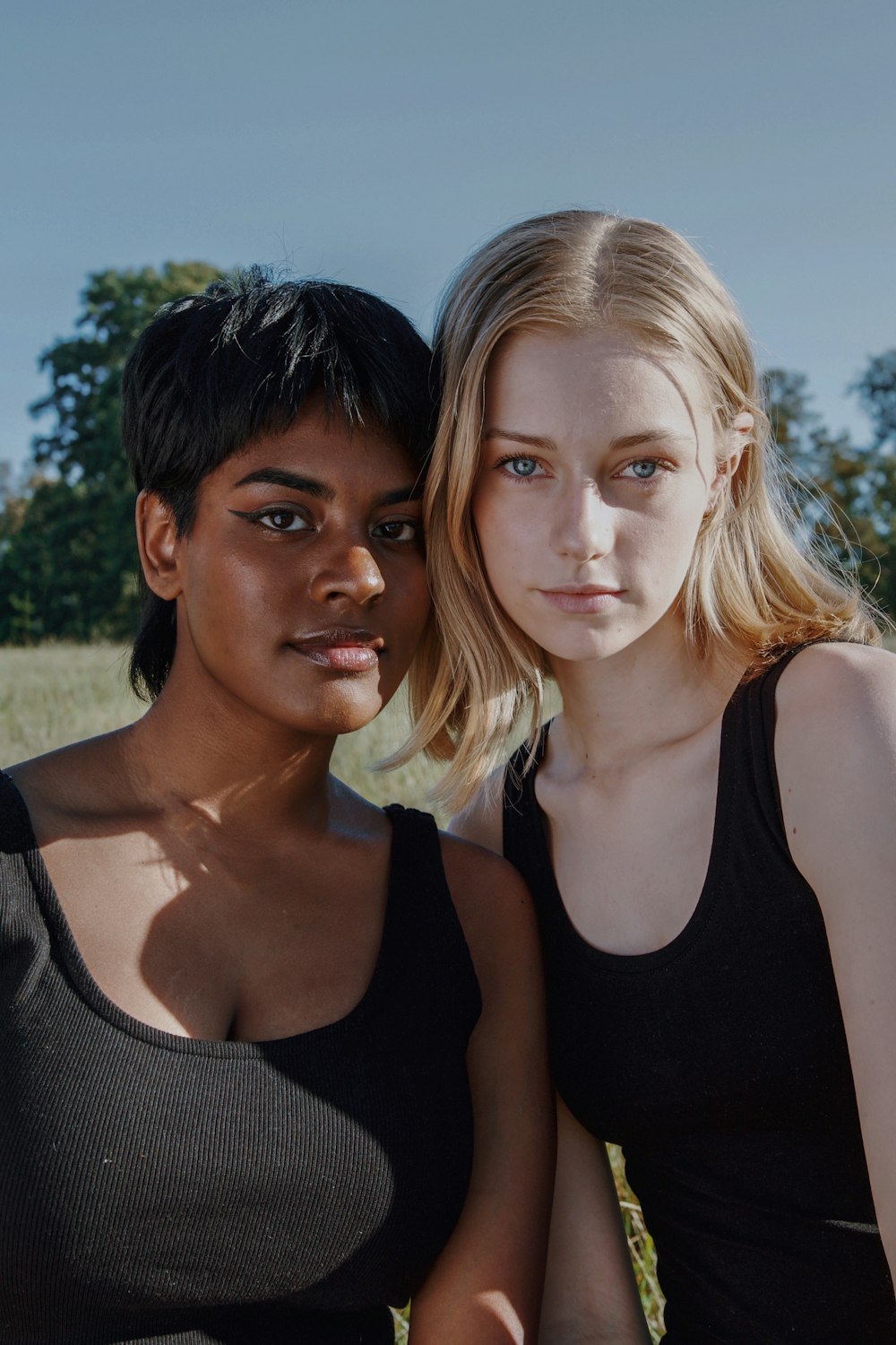 two young women sitting next to each other in a field