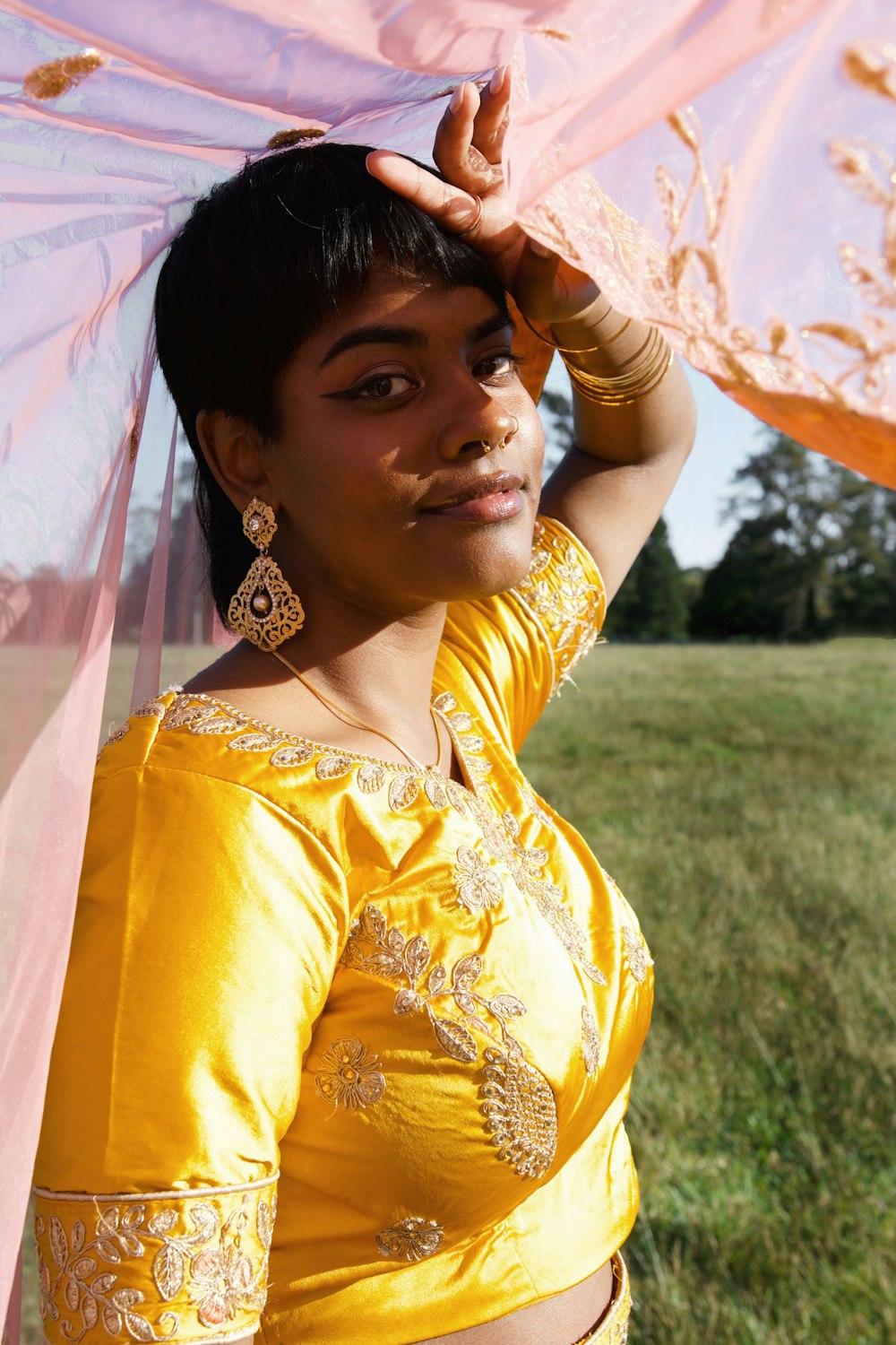 a woman in a yellow blouse holding a pink umbrella