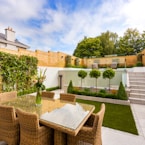 a patio with a table and chairs next to a fence