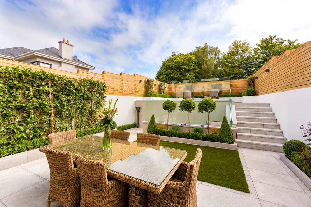 eine Terrasse mit Tisch und Stühlen neben einem Zaun