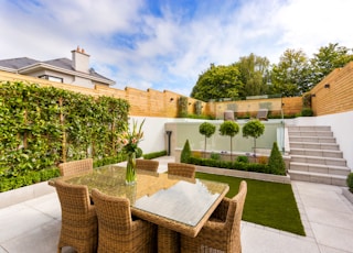 a patio with a table and chairs next to a fence