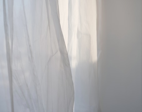 a white curtain with a cat sitting on top of it