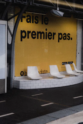 a row of white chairs sitting in front of a yellow wall