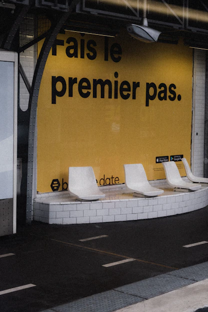 a row of white chairs sitting in front of a yellow wall