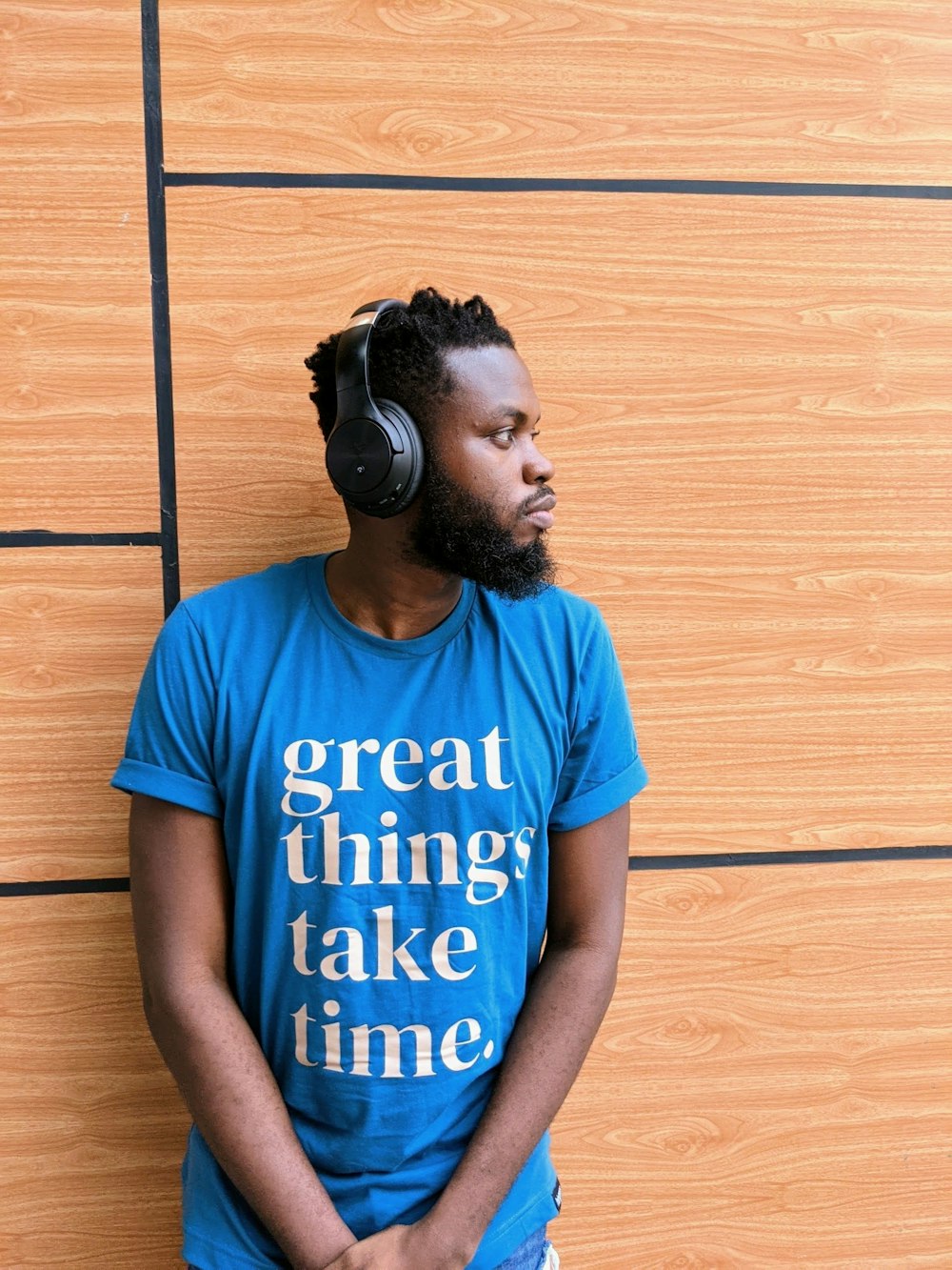a man with headphones leaning against a wall