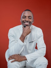 a man in a white suit posing for a picture