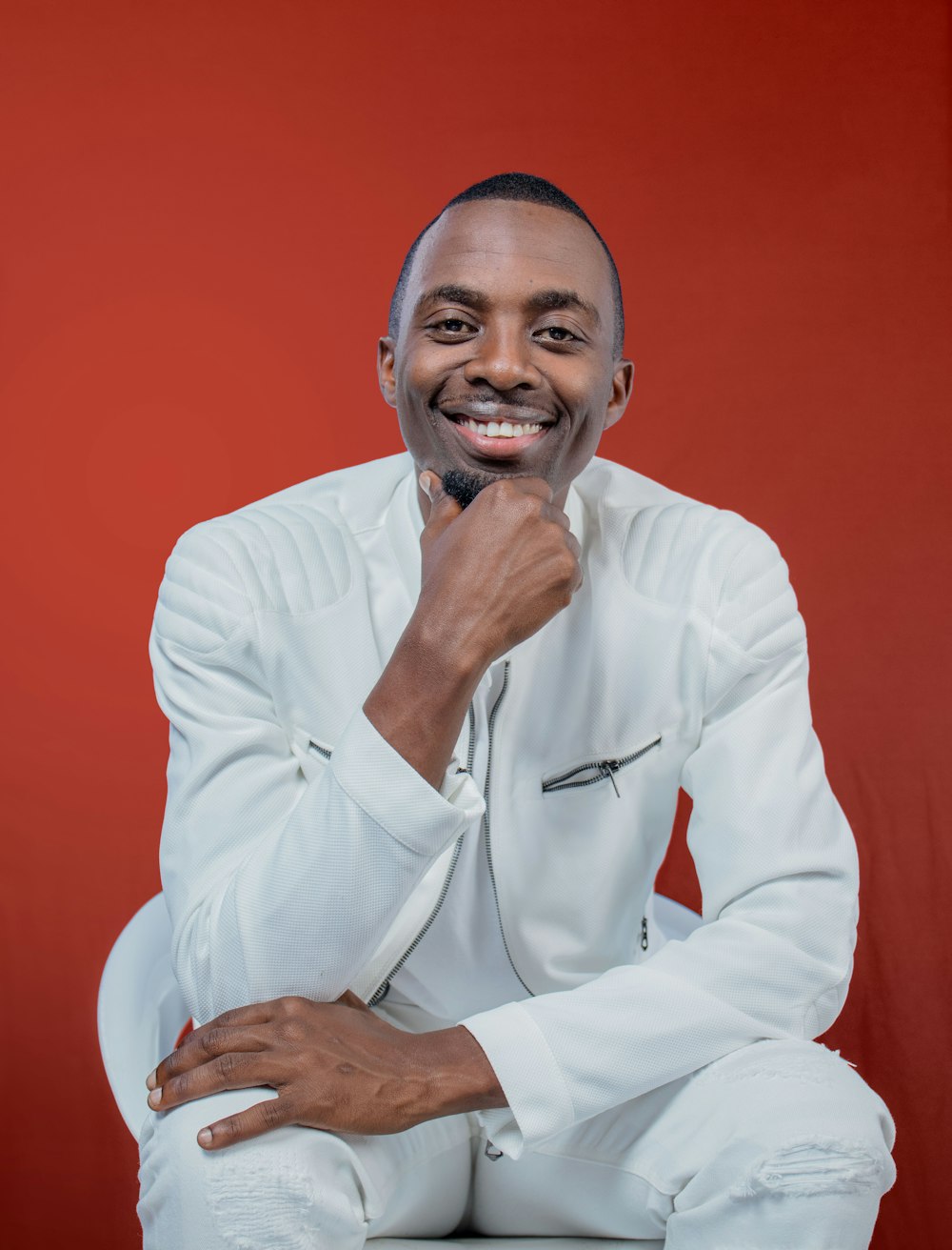 a man in a white suit posing for a picture