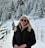 a woman in a black jacket standing in the snow
