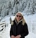 a woman in a black jacket standing in the snow