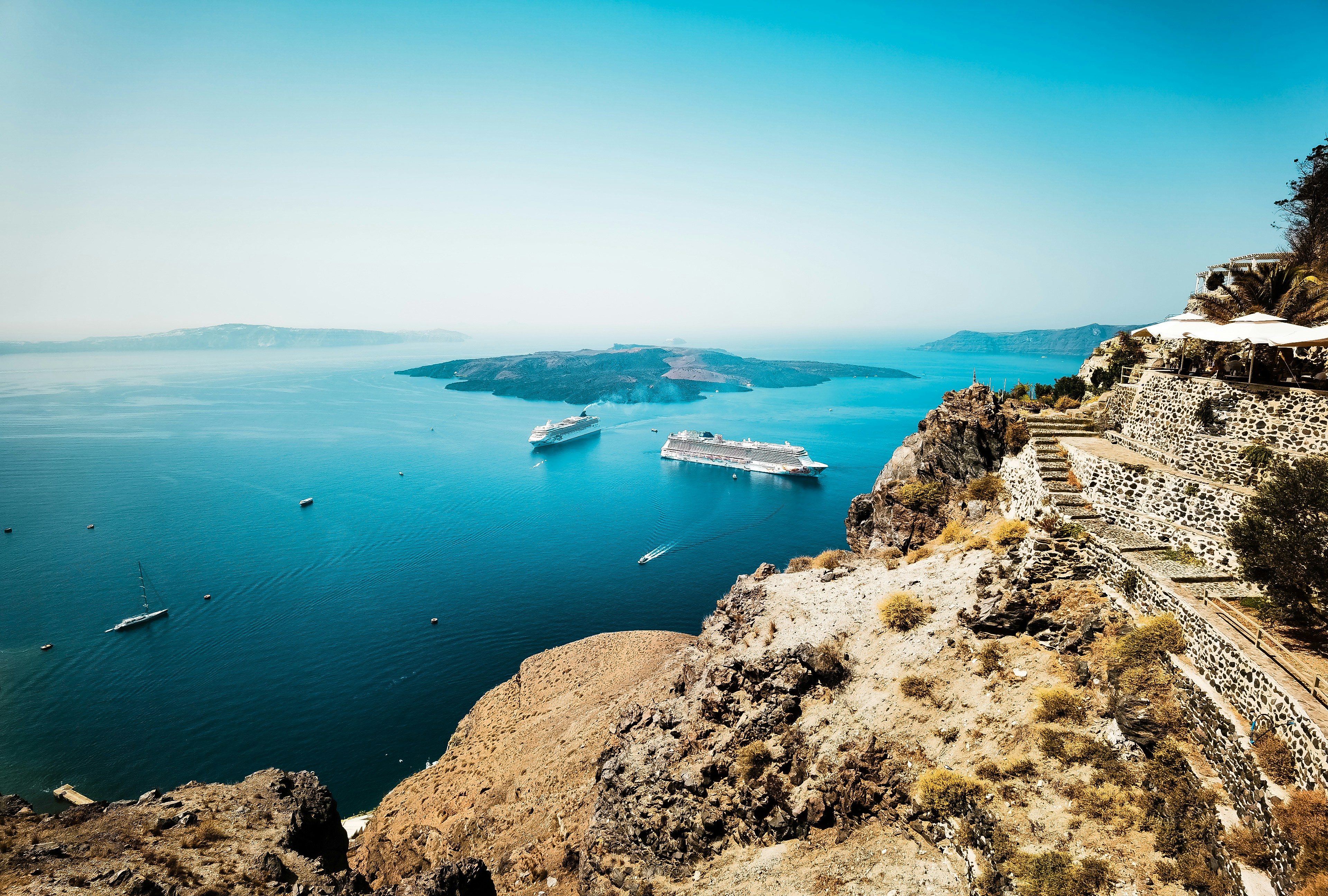 a cruise ship in the water near a rocky cliff