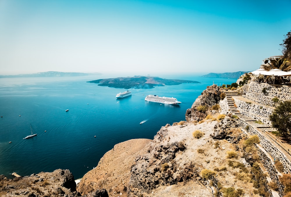 a cruise ship in the water near a rocky cliff