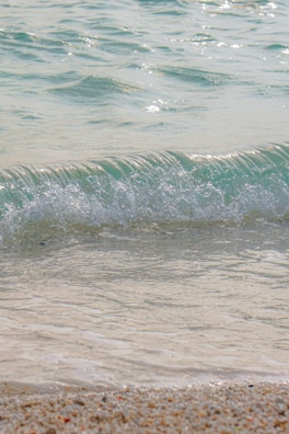 Crystal-clear ocean waves lapping against a sandy shore at dawn.