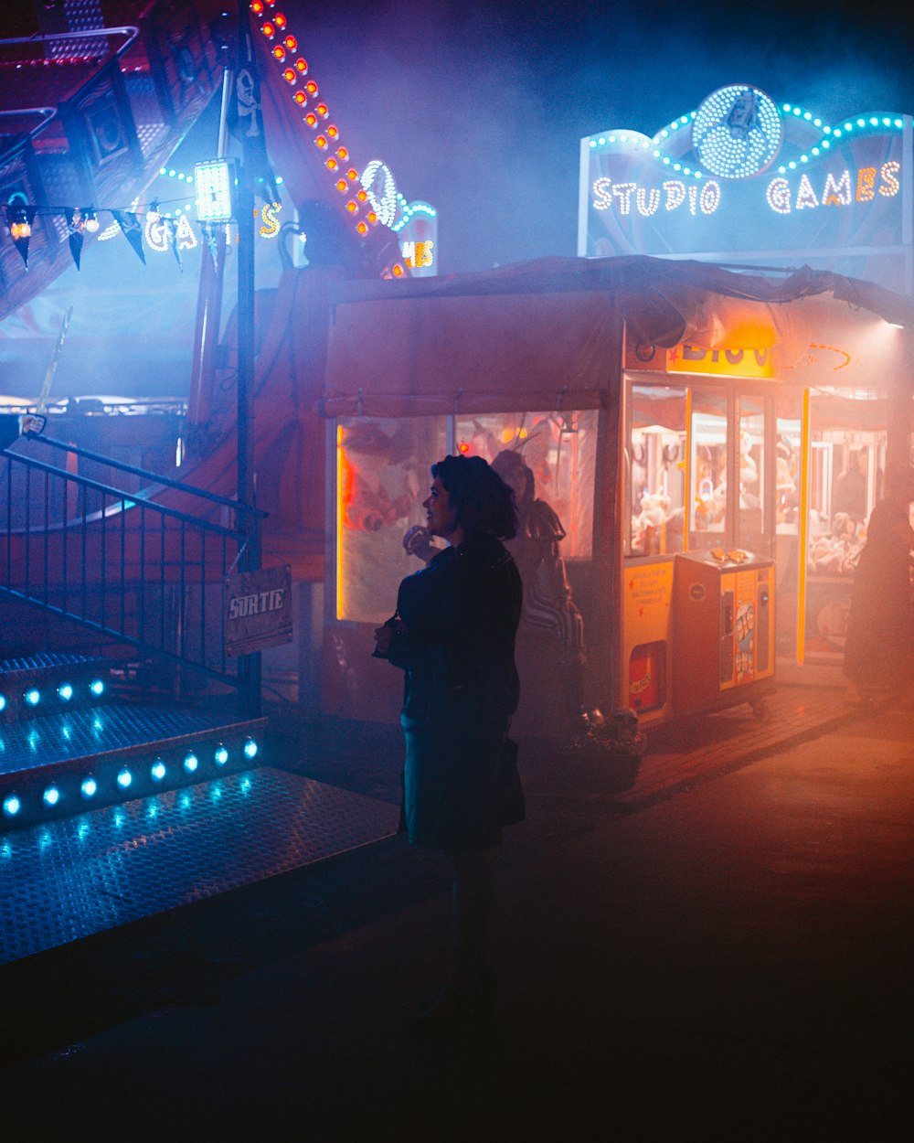 a woman standing in front of a carnival booth at night