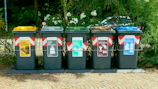 a row of trash cans sitting on top of a sidewalk