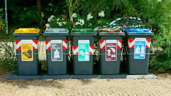 a row of trash cans sitting on top of a sidewalk