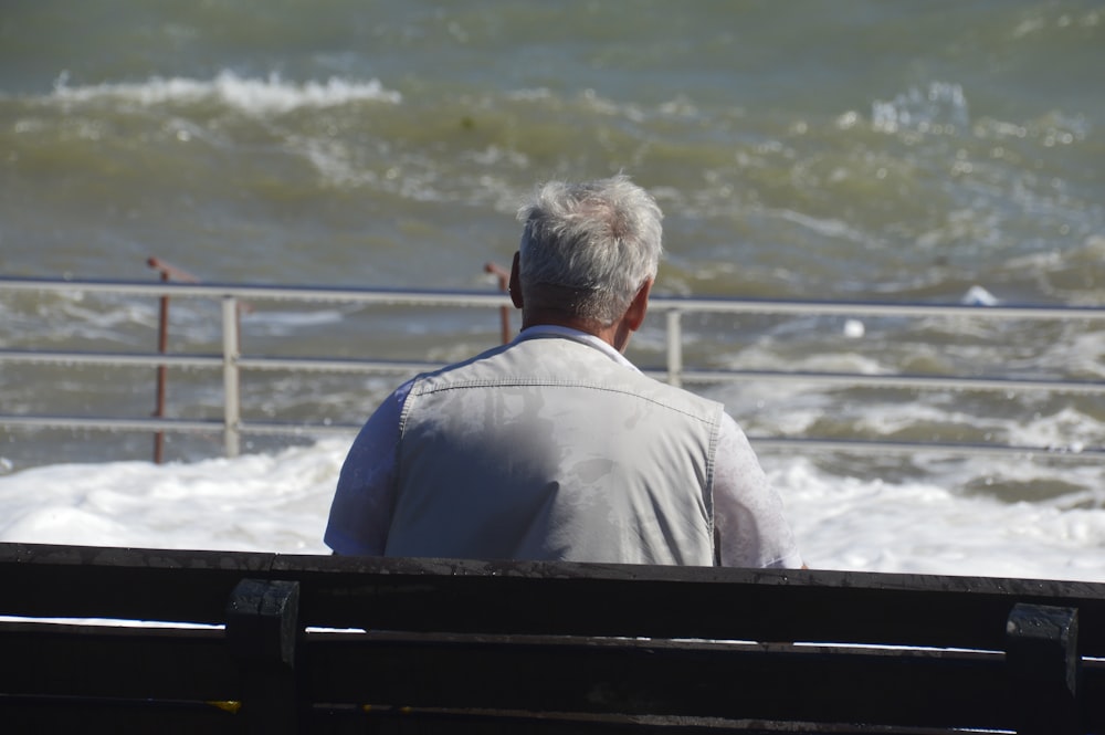 a man sitting on a bench looking at the ocean